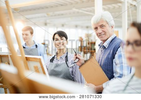 Portrait Of Mature Art Teacher Smiling At Camera Posing With Students In Class, Copy Space