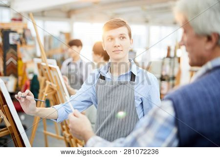 Waist Up Portrait Of Student In Art Class Looking At Teacher While Painting Picture On Easel, Copy S