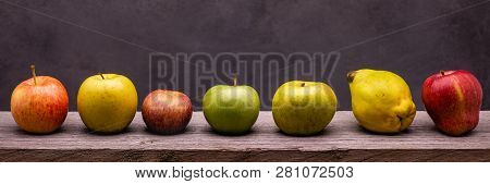 On The Rough Wooden Table, Seven Apples Of Different Types