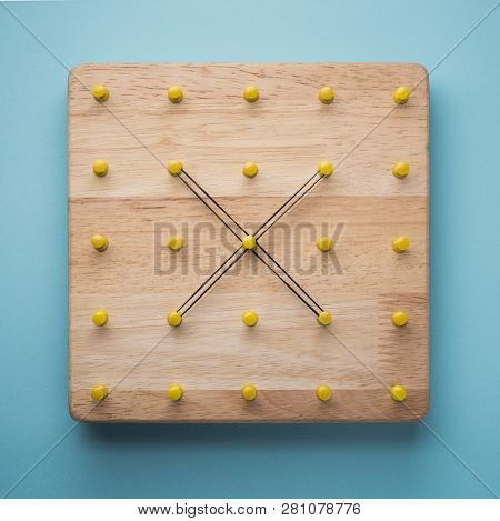 Cross sign made with stretchable rubber bands on a wooden board. Educational games or equipments. Photo 1 of 6.