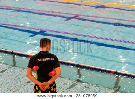 Poznan, Poland - January 26, 2019: Instructor Standing With Swim Stick Next To A Pool During Swimmin