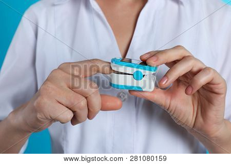 Female Doctor Holding Pulsimeter On Color Background, Closeup. Medical Object