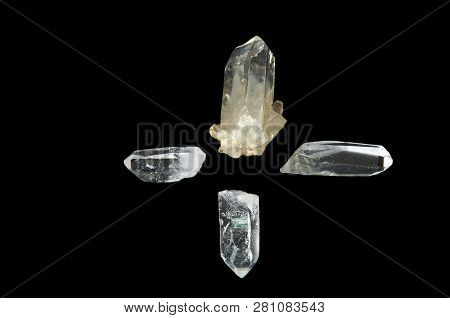 Four Clear Quartz Crystal Points On Black Background, One Pointing In Each Direction Forming A Cross