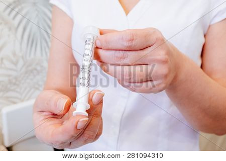 A Young Woman Doctor Distributes Portions Of Drugs In The Hospital, Determining Each Put Milliliters