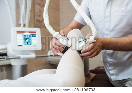 Procedure laser lipolysis of the woman hips in a beauty center.