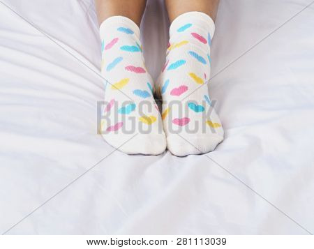 Close Up Woman Feet Wearing White Sock With Pastel Heart Shape Pattern On Bed In Bedroom. Love Conce