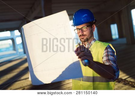 Male Young Architect With Blueprints Using Walkie-talkie