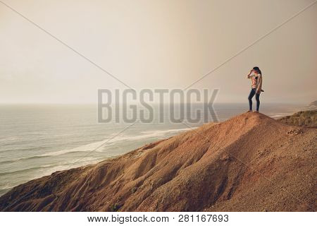 Woman on the top of a clif looking to the ocean