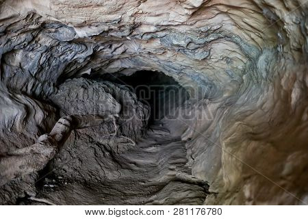 Small Dark Grotto In Layered Rock Formation. Selective Focus.