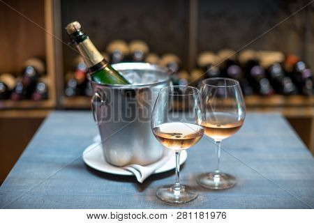 Two Cold Glasses Of Sparkling Wine. The Wall Ow Wine Bottels On Background.
