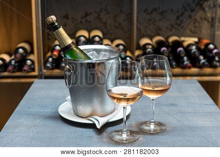 Two Cold Glasses Of Sparkling Wine. The Wall Ow Wine Bottels On Background.