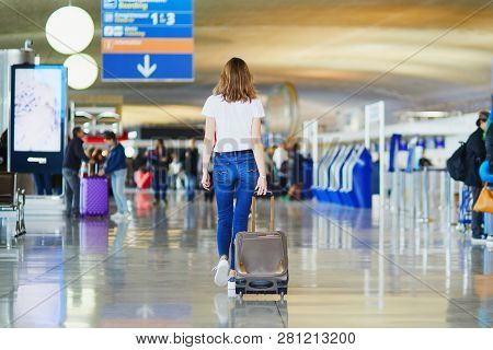 Young Woman In International Airport Walking With Luggage, Ready For Her Flight