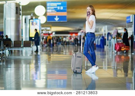 Young Woman In International Airport, Holding French Passport, Waiting For Her Flight