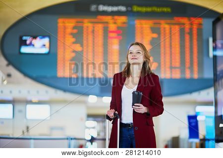 Young Woman In International Airport With Luggage And Coffee To Go Waiting For Her Flight