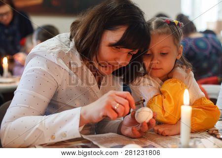 Lviv, Ukraine - March 11, 2018. Mom And Daughter Paint Easter Eggs At The Table
