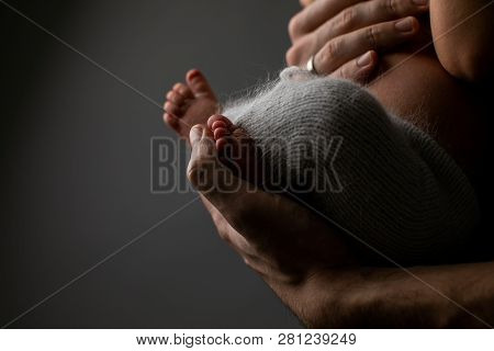 Adult Hands Holding Newborn Baby. Little Fingers