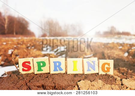 A Colorful Inscription Spring Made Up Of Wooden Cubes Stands On A Plowed Field In Spring. The Beginn