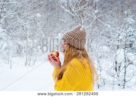 Frozen Girl In A Warm Sweater And Knitted Hat Against The Background Of The Winter Landscape Wants T