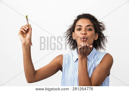 Beautiful young african woman atrist holding a paint brush over white background, sending kiss