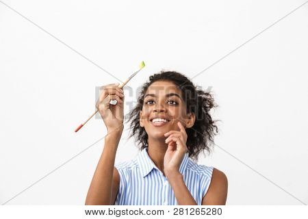 Beautiful young african woman atrist holding a paint brush over white background