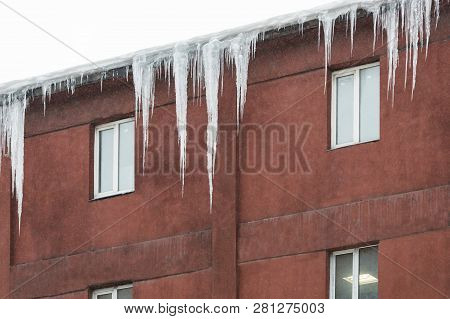 Building Covered With Big Icicles. Ice Stalactite Hanging From Roof. Poor Thermal Insulation Of The 