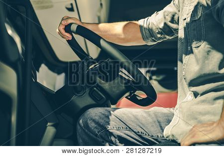 Caucasian Semi Truck Driver Behind The Wheel. Transportation Industry Concept.