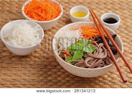 Soba noodle soup with nori seaweed sheets, green beans, carrot, daikon radish, and soy sauce