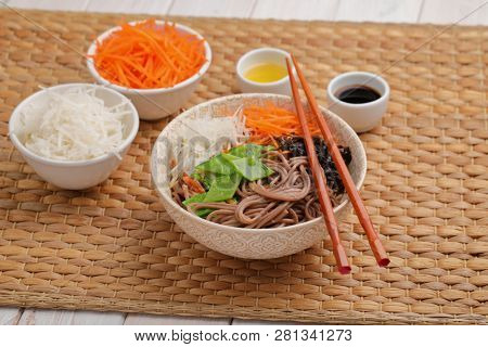 Soba noodle soup with nori seaweed sheets, green beans, carrot, daikon radish, and soy sauce