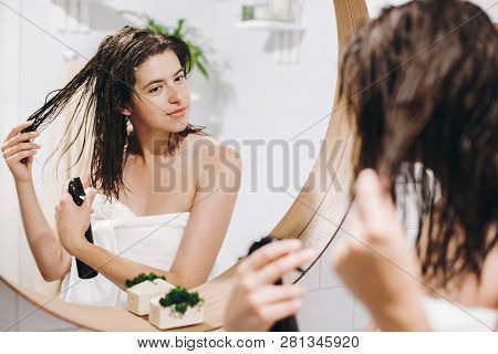 Hair And Body Care. Young Happy Woman In White Towel Applying Conditioner Mask On Hair In Bathroom, 