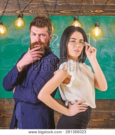 Man With Beard And Teacher In Eyeglasses Stand Back To Back, Chalkboard On Background. Teacher And S