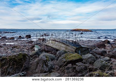 Rowing Boat Upsidedown On A Rocky Beach