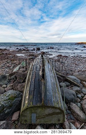 Rowing Boat Upsidedown On A Rocky Beach