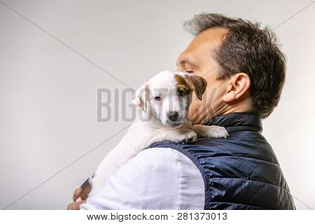 Horizontal Portrait Of Handsome Cheerful Man Holds Jack Russell Terrirer, Has Glad Expression