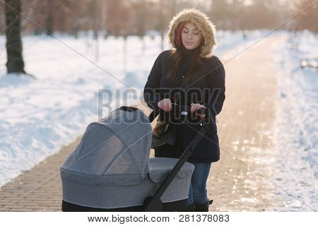 Mom Walk With Baby In Pram. Winter Park. Happy Woman With Her Baby