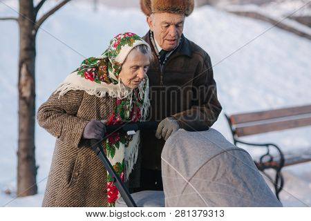 Grand Grandparents Walking With A Baby In Beautiful Pram. Winter Time