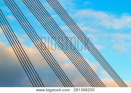 Parallel Guyes Of A Cable-stayed Bridge Located Diagonally Against A Blue And Cloudy Sky. Architectu