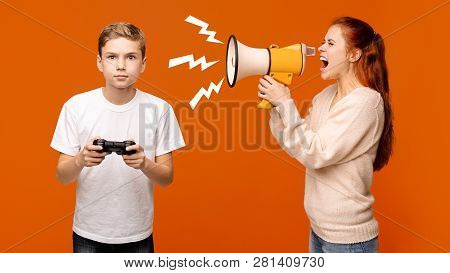 Problems Of Modern Kids. Mad Woman Shouting With Megaphone At Addicted Boy, Playing Video Game With 