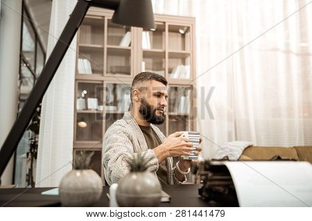 Serious Thoughtful Man In Knitted Cardigan Carrying Big Cup Of Tea