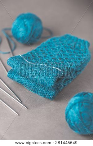A Pair Cozy Blue Socks With Two Ball Of Yarn And Five Stainless Steel Dpn Knitting Needles On Gray B