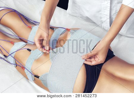 The Procedure Of Myostimulation On The Legs And Buttocks Of A Woman In A Beauty Salon. Caring For Th