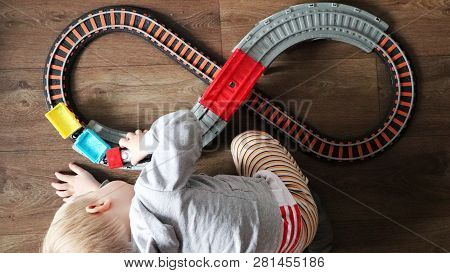A Little Boy Plays A Children's Railway. Mom Is Watching Her Son From Above. The Child Is Fascinated