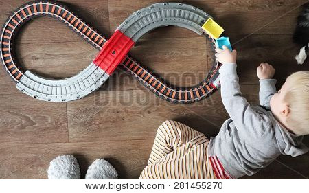 A Little Boy Plays A Children's Railway. Mom Is Watching Her Son From Above. The Child Is Fascinated