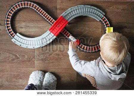 A Little Boy Plays A Children's Railway. Mom Is Watching Her Son From Above. The Child Is Fascinated