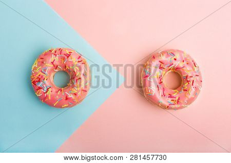 Two Donuts Decorated With Sprinkles On Colorful Background. Coral And Blue Color Background