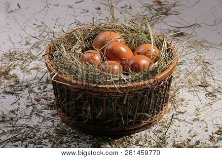 Six Eggs Lying On A Hay In A Basket. Easter Or Village Theme.