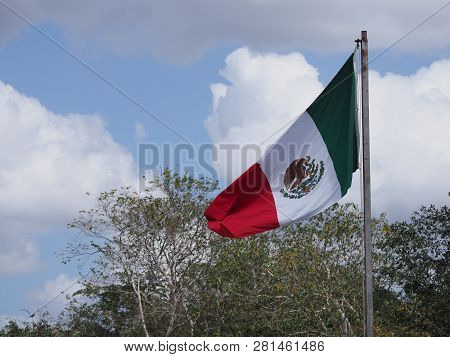 National Maxican Flag At Chichen Itza City Near Brilliant Archaeological Site In Mexico With Trees A