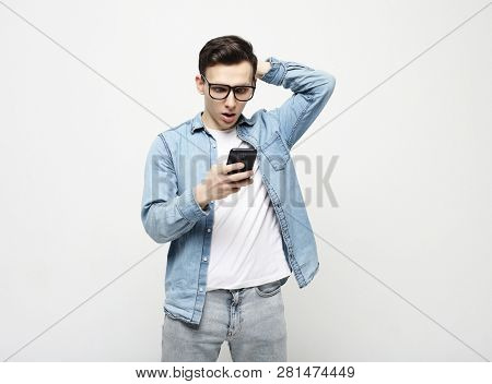  Happy young  man in glasses typing sms on white background