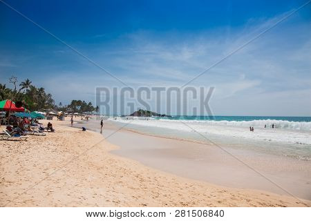 Mirissa Beach, Sri Lanka - JAN 2, 2017:  Tourists walking on the sand while enjoying the view across the wonderful beach of Mirissa on Jan 2, 2017. Sri Lanka.