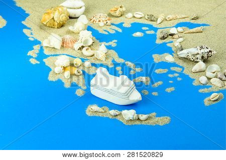 Cruise Liner Off The Coast Of Greece. The Map Is Made Of Sand, With Seashells On Top.