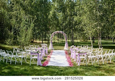 Place For Wedding Ceremony. Wedding Arch Decorated With Cloth And Flowers And Chairs On Each Side Of
